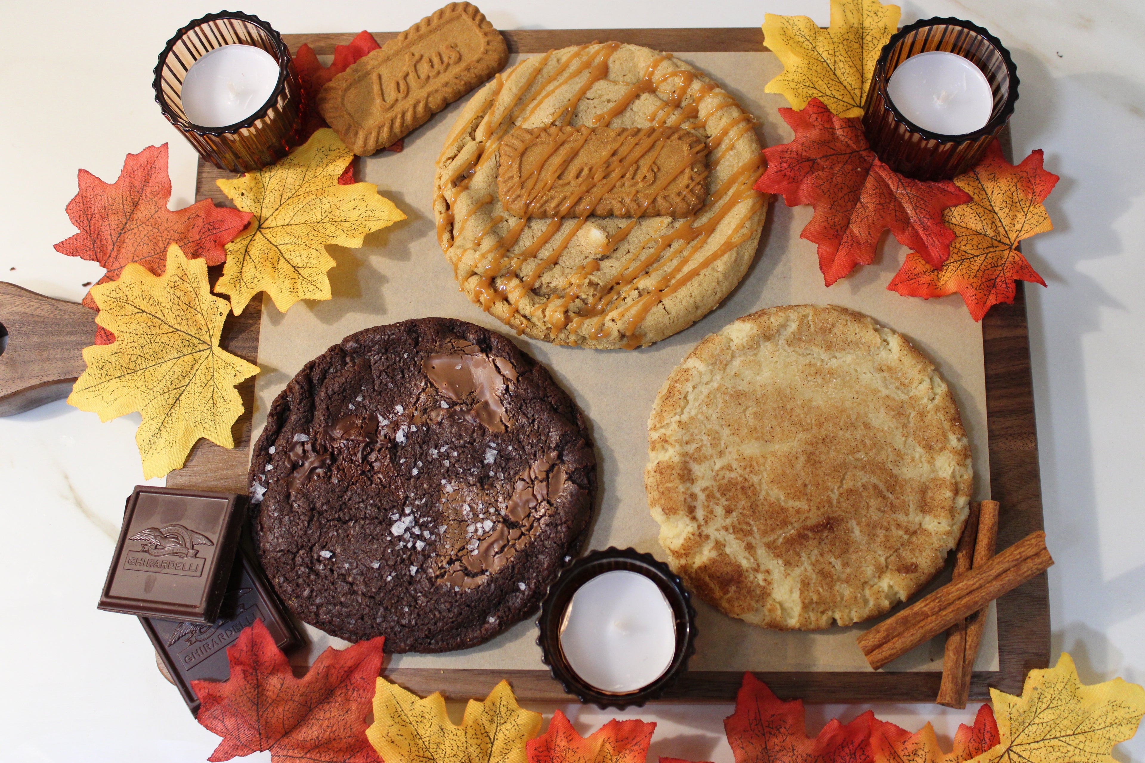 Assorted pies on a wooden board with autumn leaves and candles